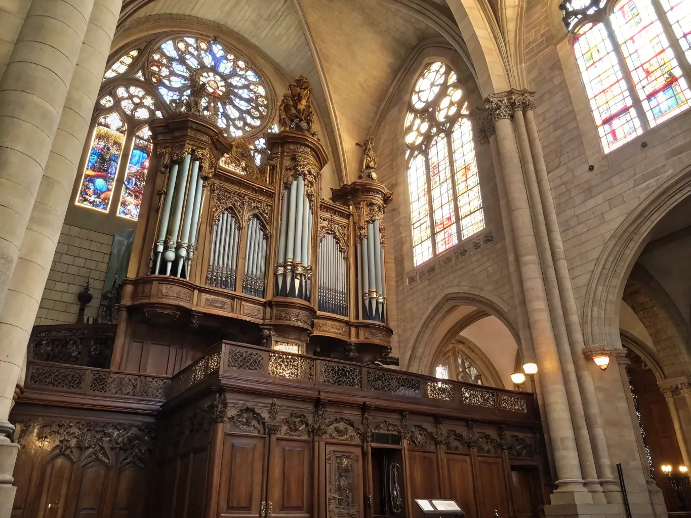 A beautifully lit pipe organ in a historic church, bathed in soft, golden light during an evening concert. The focus is on the intricate details of the organ pipes and the grandeur of the setting.